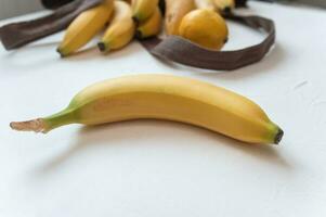 dolce maturo giallo frutta Banana e limoni nel shopping Borsa su tavolo. isolato bianca sfondo. salutare tropicale cibo foto