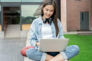 bellissimo asiatico donna femmina alunno eccitato controllo linguaggio test risultati su il computer portatile. Sorridi ragazza contento studia in linea. libro nel Università città universitaria. ritratto femmina su internazionale Asia Università foto