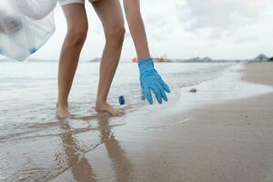 Salva acqua. volontario raccogliere su spazzatura spazzatura a il spiaggia e plastica bottiglie siamo difficile decomporsi impedire danno acquatico vita. terra, ambiente, greening pianeta, ridurre globale riscaldamento, Salva mondo foto