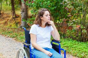 giovane contento handicap donna nel sedia a rotelle su strada nel ospedale parco in attesa per paziente Servizi. paralizzato ragazza nel non valido sedia per Disabilitato persone all'aperto nel natura. reinserimento concetto. foto