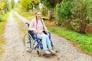 giovane contento handicap donna nel sedia a rotelle su strada nel ospedale parco in attesa per paziente Servizi. paralizzato ragazza nel non valido sedia per Disabilitato persone all'aperto nel natura. reinserimento concetto. foto