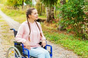 giovane contento handicap donna nel sedia a rotelle su strada nel ospedale parco in attesa per paziente Servizi. paralizzato ragazza nel non valido sedia per Disabilitato persone all'aperto nel natura. reinserimento concetto. foto