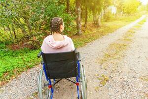 giovane contento handicap donna nel sedia a rotelle su strada nel ospedale parco in attesa per paziente Servizi. paralizzato ragazza nel non valido sedia per Disabilitato persone all'aperto nel natura. reinserimento concetto. foto