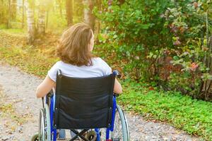 giovane contento handicap donna nel sedia a rotelle su strada nel ospedale parco godendo libertà. paralizzato ragazza nel non valido sedia per Disabilitato persone all'aperto nel natura. reinserimento concetto. foto