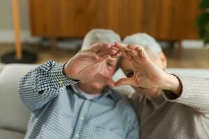 amore cuore forma pace. anziano più vecchio coppia fabbricazione cuore forma con loro mani. adulto maturo vecchio marito moglie mostrando cuore cartello. contento pensionato famiglia. io amore voi contento san valentino giorno. foto