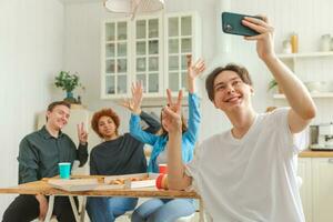 Saluti impaurito umore. contento gruppo di amici rendere autoscatto. uomo assunzione foto di amici a festa. gruppo di multirazziale giovane persone assunzione foto su Telefono. giovane persone godere loro azienda Sorridi avere divertimento.