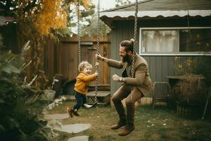 un' papà spingendo il suo bambino su un' swing nel il Giardino dietro la casa foto