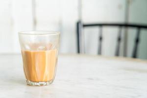 bicchiere di tè al latte tailandese caldo sul tavolo foto