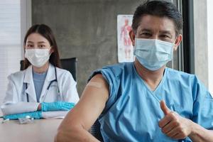 paziente maschio asiatico con maschera facciale pollice in su con una dottoressa.