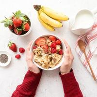 colazione sana, cereali, frutti di bosco freschi e latte in una ciotola, vista dall'alto foto