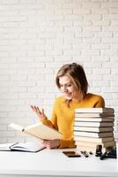 giovane donna sorridente in maglione giallo che legge un libro e ride foto