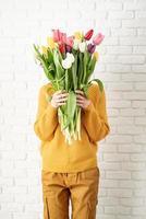bella donna felice in vestiti gialli che tiene mazzo di tulipani