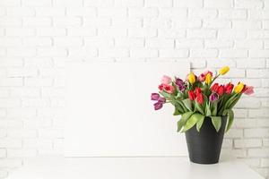 mock up con cornice e secchio di tulipani su sfondo bianco muro di mattoni foto