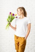 donna che indossa una maglietta bianca vuota con in mano fiori di tulipano