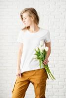 donna che indossa una maglietta bianca vuota con in mano fiori di tulipani