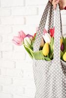 mano di donna che tiene borsa in tessuto a pois grigi con tulipani colorati