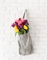 borsa grigia in tessuto a pois piena di tulipani colorati foto