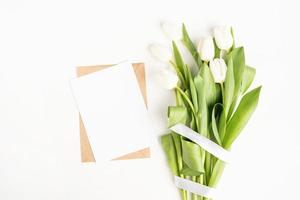 fiori di tulipano e carta bianca con busta vista dall'alto foto