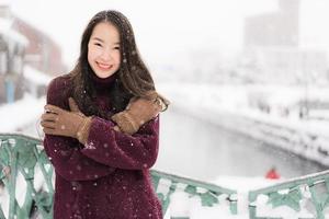 donna asiatica sorridente felice per il viaggio nella stagione invernale di neve? foto