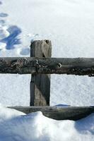 un' di legno recinto con un' neve coperto terra foto