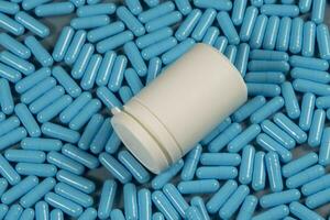 blu antibiotico capsula pillole struttura con bianca bottiglia. farmaceutico produzione. globale Salute. resistenza per antibiotico droghe. gelatina capsula pillole foto