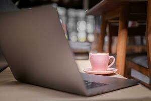 un' il computer portatile su il tavolo con un' tazza di caffè. foto