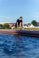 giovane, in forma e sportivo ragazza nel nero Abiti allungamento dopo il allenarsi vicino il pubblico Fontana nel il urbano città parco. foto