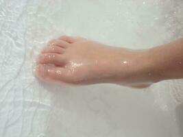 un' di persona spoglio piedi nel un' vasca da bagno foto