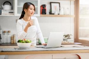 donna asiatica che fa una pausa caffè mentre lavora da casa foto