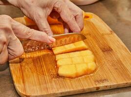 capocuoco tagli melone in cubi su di legno tavola nel il cucina foto