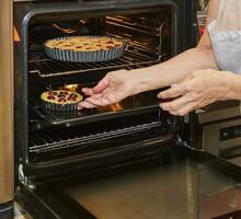 posti il preparato ciliegia torta pentole in il elettrico forno per cottura al forno foto