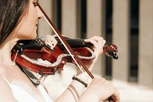 donna artista con buio capelli nel un' vestito giochi un' di legno concerto elettrico violino foto