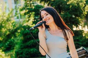 donna cantante con buio capelli nel un' vestito canta in un' microfono foto