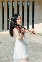 donna artista con buio capelli nel un' vestito giochi un' di legno concerto elettrico violino foto