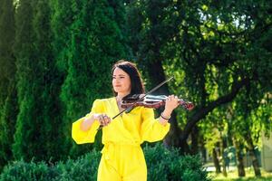 donna artista con buio capelli nel un' vestito giochi un' di legno concerto elettrico violino foto