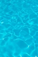 azzurro trasparente struttura di acqua nel un' blu piscina con spruzzi a partire dal il sole foto