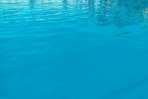 azzurro trasparente struttura di acqua nel un' blu piscina con spruzzi a partire dal il sole foto