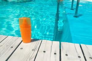 spray protezione solare sta su il sfondo di il piscina foto