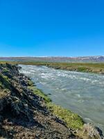 islandese paesaggio con fluente fiumi circondato di rocce e erba. foto