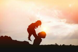 un' silhouette di un' contento giovane madre armonioso famiglia all'aperto. ridendo e giocando nel il estate su il tramonto background.sstkhome foto