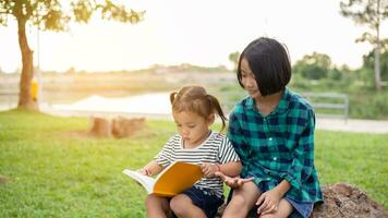 carino poco ragazza lettura libro su albero nel park.sstkhome foto