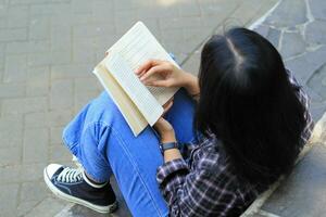 contento memore giovane asiatico donna Università alunno lettura un' libro nel il parco, formazione scolastica concetto foto