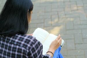 contento memore giovane asiatico donna Università alunno lettura un' libro nel il parco, formazione scolastica concetto foto