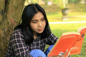 contento memore giovane asiatico donna Università alunno lettura un' libro nel il parco, formazione scolastica concetto foto