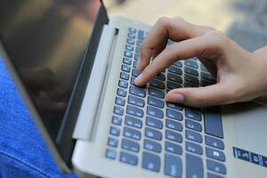 vicino su tiro donna d'affari mano digitando su il computer portatile tastiera foto