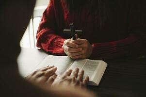 Due persone lettura e studia Bibbia nel casa e pregare insieme.studiando il parola di Dio con gli amici. nel sole leggero foto