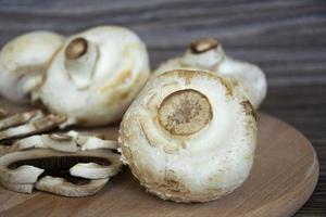 primo piano di funghi prataioli. i funghi champignon giacciono su uno sfondo di legno foto