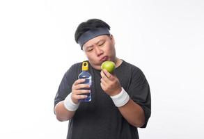 il giovane uomo grasso asiatico sceglie la mela verde foto