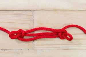 nodo di stinco di pecora realizzato con corda rossa su fondo di legno. foto