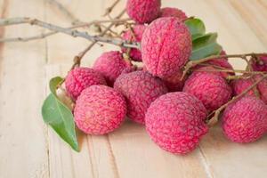 grande litchi rosso su sfondo tavolo in legno, messa a fuoco selettiva foto